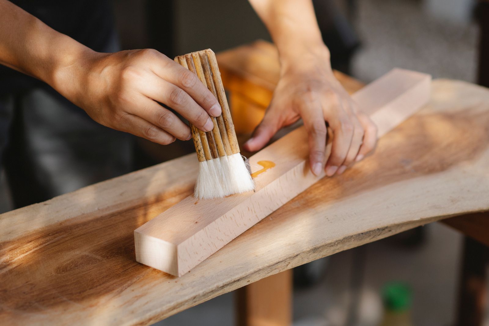 Careful hands finishing a piece of wood — close-up craftsmanship on a small project